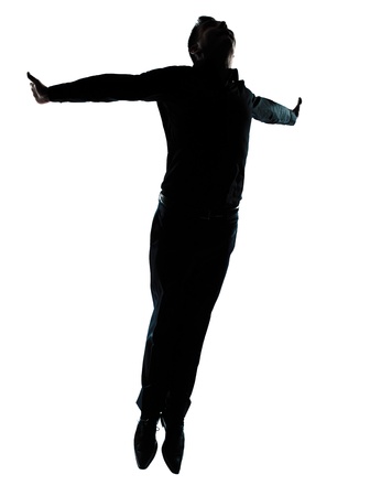 one caucasian business man  jumping flying wellness silhouette Full length in studio isolated on white backgroundの写真素材