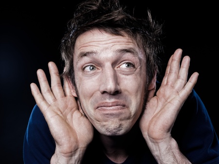 studio portrait on black background of a funny expressive caucasian man with hearing problem