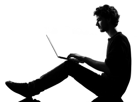 young man silhouette silhouette sitting computing computer laptop in studio isolated on white backgroundの写真素材