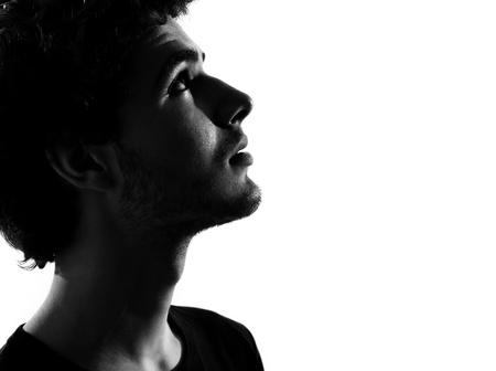 young man looking up portrait silhouette in studio isolated on white backgroundの写真素材