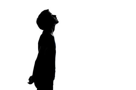 one caucasian young teenager silhouette boy or girl looking up portrait in studio cut out isolated on white backgroundの写真素材
