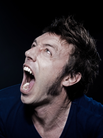 studio portrait on black background of a funny expressive caucasian man screamingの写真素材