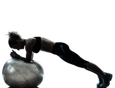 one caucasian woman exercising fitness ball workout posture in silhouette studio isolated on white backgroundの写真素材