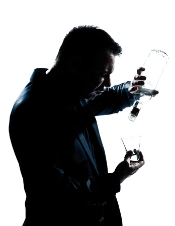 one caucasian man portrait silhouette drunk puring empty alcohol botlle in studio isolated white backgroundの写真素材