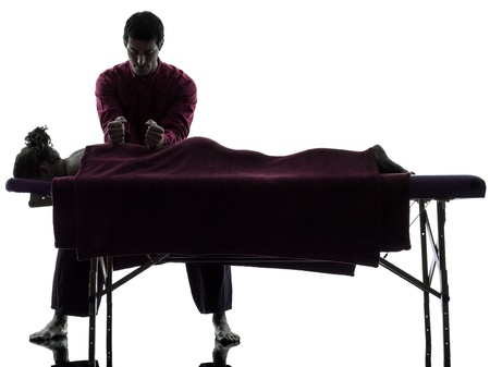 man woman back massage in silhouette studio on white backgroundの写真素材