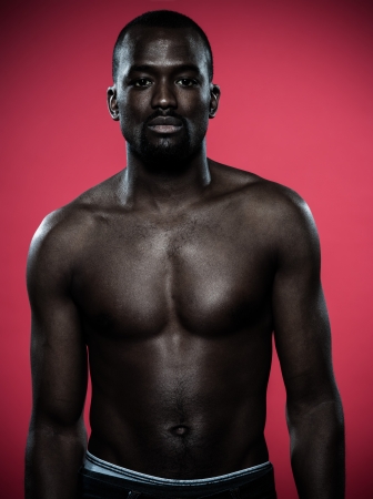 one young handsome african man topless portrait in studio on red backgroundの写真素材