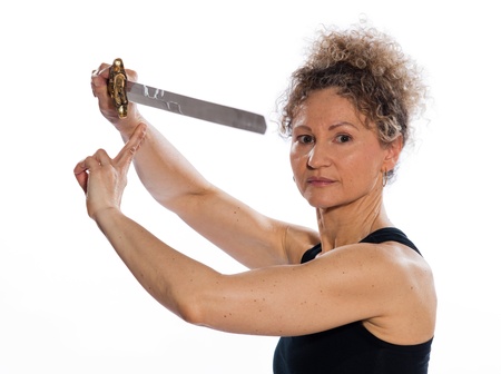 mature woman praticing tai chi chuan with sword in studio on isolated white backgroundの写真素材