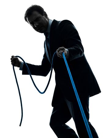 one caucasian business man pulling a rope in silhouette studio isolated on white backgroundの写真素材