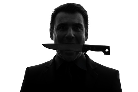 one caucasian man biting knife in silhouette studio isolated on white backgroundの写真素材