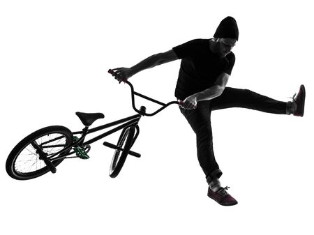 one caucasian man exercising bmx acrobatic figure in silhouette studio isolated on white backgroundの写真素材