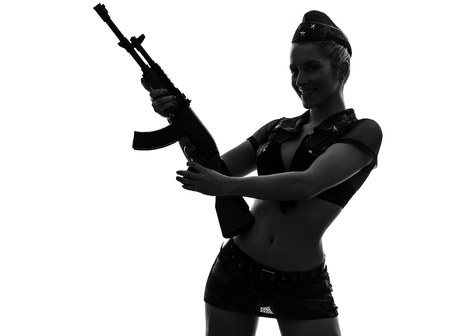 one caucasian sexy woman in army uniform holding kalachnikov in silhouette studio isolated on white backgroundの写真素材