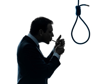 one caucasian man smoking cigarette  standing in front of hangman's noose in silhouette studio...