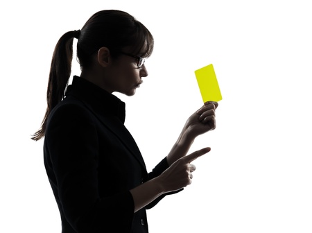 one caucasian business woman showing yellow card  in silhouette studio isolated on white backgroundの写真素材