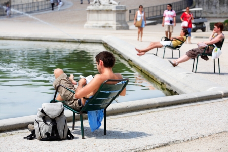 tourist resting and reading in a park of paris during summer heat waveのeditorial素材