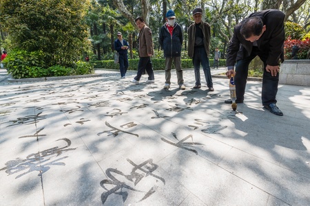 Shanghai, China - April 7, 2013 man writing  chinese calligraphy with water  in fuxing park at the...