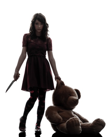 one caucasian strange young woman holding  bloody knife an teddy bear in silhouette white backgroundの写真素材