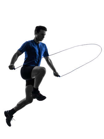 one caucasian man exercising jumping rope in silhouette studio  on white backgroundの写真素材
