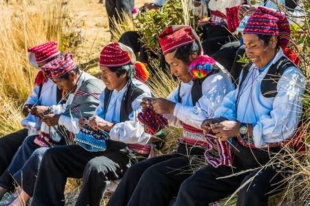 Puno, Peru - July 25, 2013: men weaving in the peruvian Andes at Taquile Island on Puno Peru at july 25th, 2013.のeditorial素材