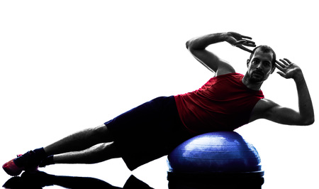 one man exercising fitness bosu balance trainer  in silhouette isolated on white backgroundの写真素材