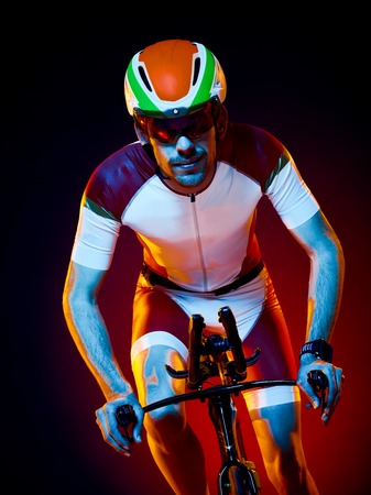 one caucasian man cyclist cycling bicycle triathlon isolated on black backgroundの写真素材