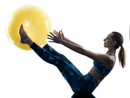 one caucasian woman exercising fitness swiss ball excercises in silhouette isolated on white backgroundの写真素材