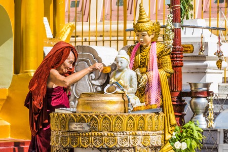 buddhist monk watering buddha statue Shwedagon Pagodaのeditorial素材