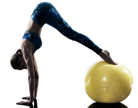 one caucasian woman exercising fitness swiss ball excercises in silhouette isolated on white backgroundの写真素材