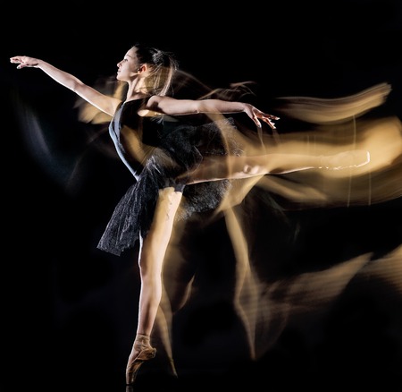 one caucasian young woman ballerina dancer dancing isolated on black background with  light painting motion blur speed effectの写真素材