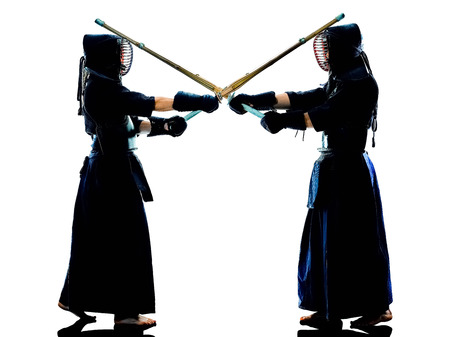two Kendo martial arts fighters combat fighting in silhouette isolated on white bacgroundの写真素材