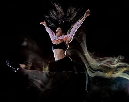 one caucasian young woman modern  dancer dancing isolated on black background with  light painting motion blur speed effectの写真素材