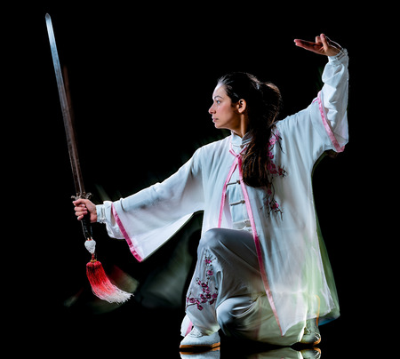 one chinese woman partacticing  Tai Chi Chuan Tadjiquan posture studio shot isolated on black background  with light painting effectの写真素材