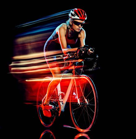 one caucasian woman triathlon triathlete cyclist cycling studio shot isolated on black background with light painting effectの写真素材