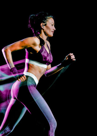 one beautiful caucasian mixed race woman unner jogger jogging running in studio isolated on black backgroundの写真素材