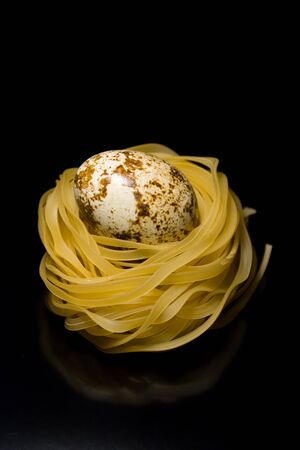 spaghetti nests with eggs for the design on a black backgroundの写真素材