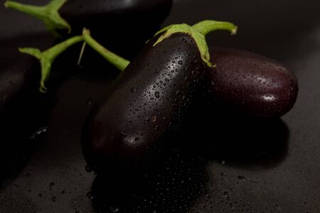 Two eggplant in the center of juicy kali water on a black backgroundの写真素材