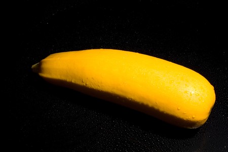 vegetable marrow on a black background with water drops of fresh juicy yellowの写真素材