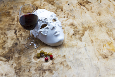 Red wine glass with whie mask on wood backgroundの写真素材