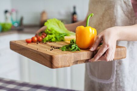 Woman holds a tray with pepper, lettuce, tomatoes, cheese and spices, closeupの写真素材