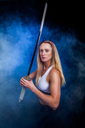 Portrait of beautiful sportswoman woman with katana in studioの写真素材