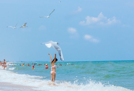 Beautiful young girl flying with seagulls on the sea, hands upの写真素材