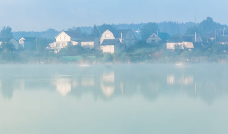 mystic fog is running on the lake in the cold summer morning.の写真素材