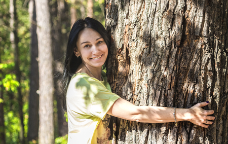 Happy beautiful girl hugging big tree in forest, smiling. save treeの写真素材