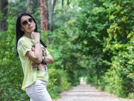 Beautiful girl with basket of lupine flowers on rural road near green fieldの写真素材
