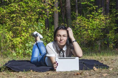 Young woman laying on the lawn with her white tablet computerの写真素材