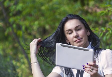 Young woman standing in the woods with her white tablet computerの写真素材