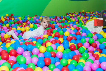 little smiling girl playing in colorful balls park playgroundの写真素材
