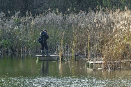 man fisherman catches a fish in the river from the bridgeの写真素材