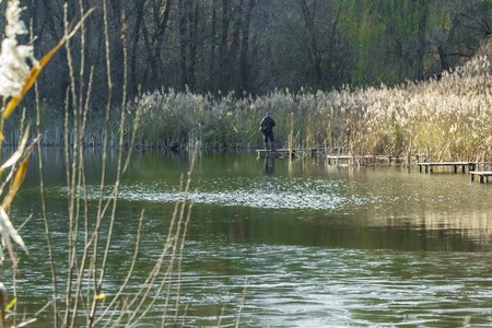 man fisherman catches a fish in the river from the bridgeの写真素材