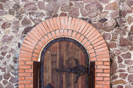 Wooden old door in red brick wall backgroundの写真素材