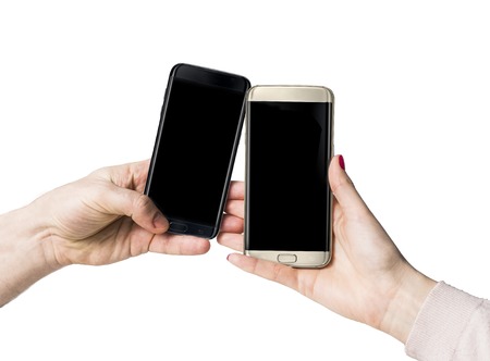 Gold and black smart phones with with blank blue screen copy space in female human hand isolated on white backgroundの写真素材